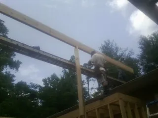 Carpenter setting a ridge beam over a new addition frame — Ice Dam Removal by Roofing Brothers in Coldwater