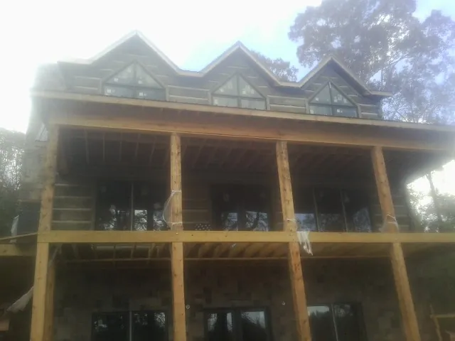 Dormers and porch framing on a large log home under construction — Roof Coating work by our crew in Coldwater